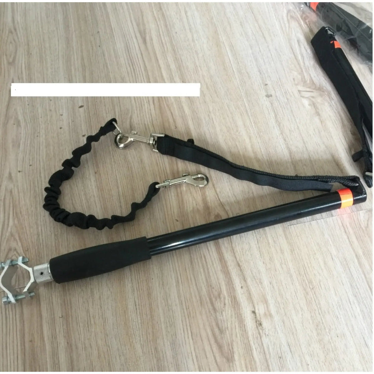 Bicycle dog leash with orange accent strap, silicone grip and bungee lead on a wooden table