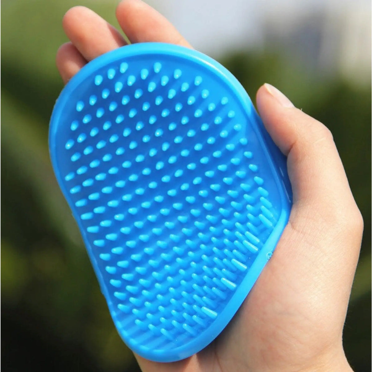 Hand holding a blue rubber pet bath brush showing massaging nubs