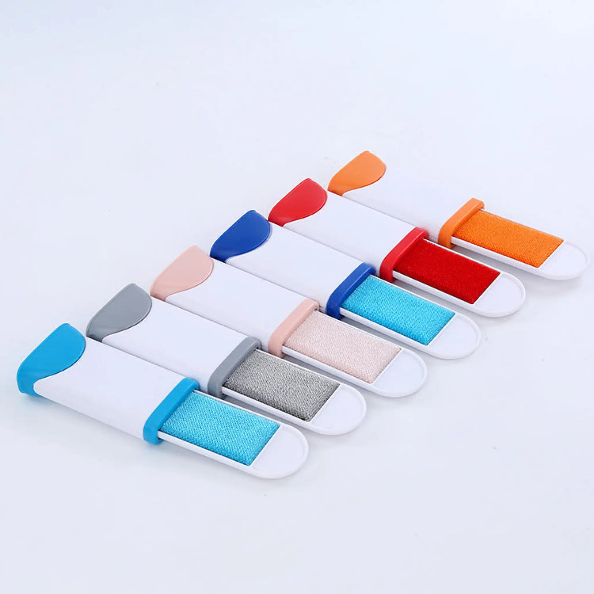 Six pet hair remover brushes with colored fabric pads lined up in assorted colors