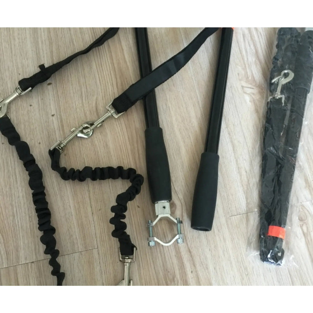 Black bicycle dog leash components with clamp, bungee leads and rods on a wooden surface