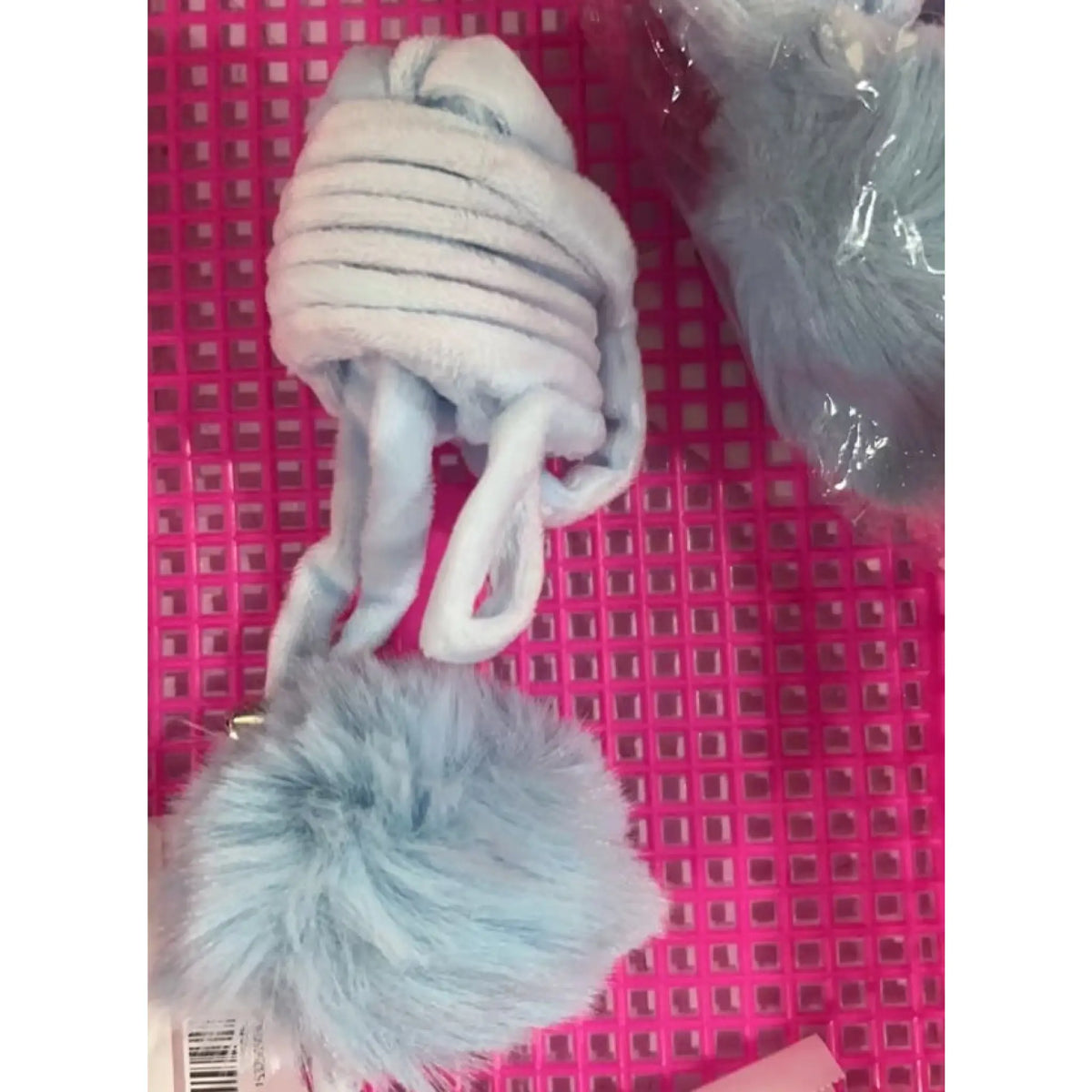 Light blue plush spring coil with loop strap and fluffy pom-pom ball on a pink tray