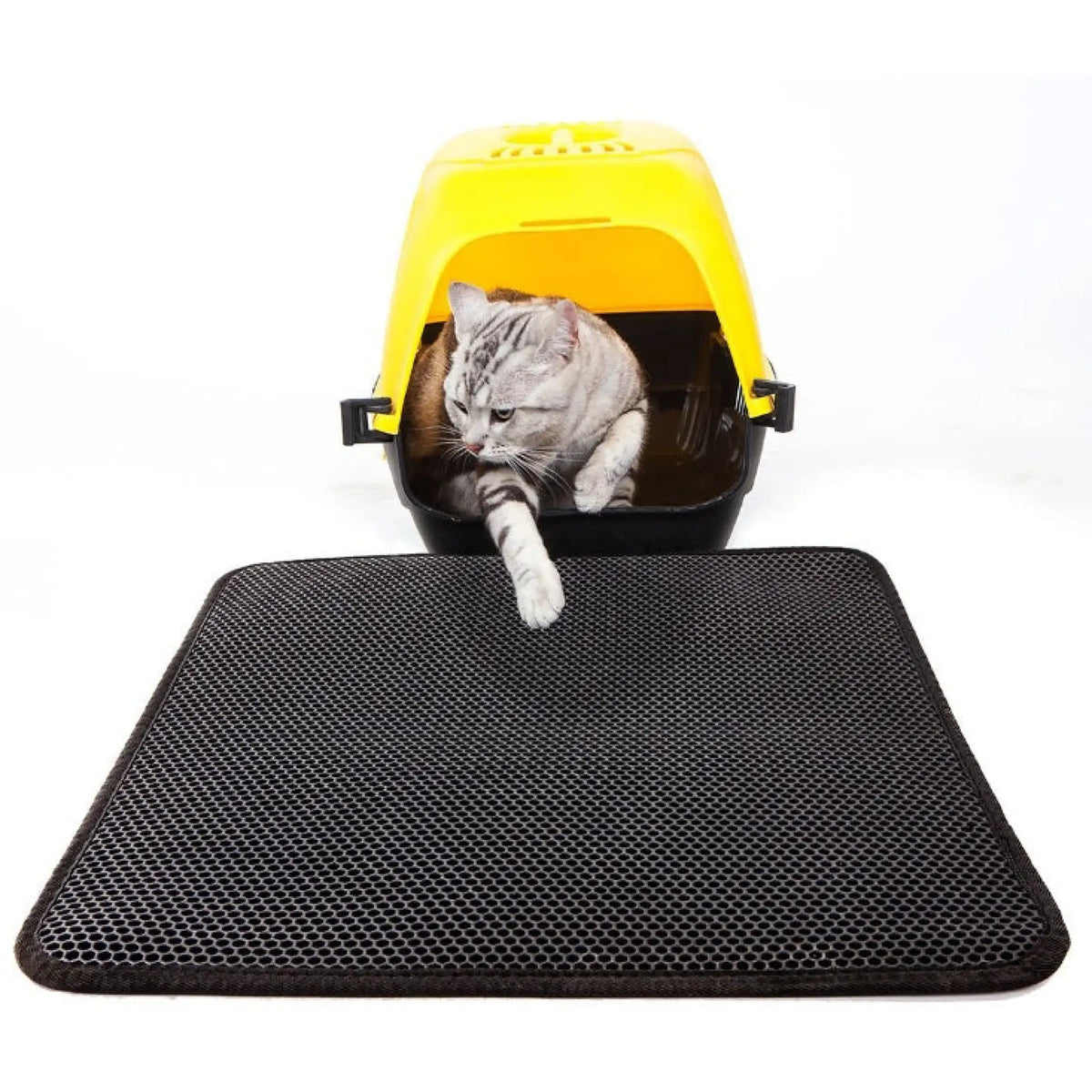 Black honeycomb EVA litter mat placed in front of a yellow covered cat litter box with a cat stepping out