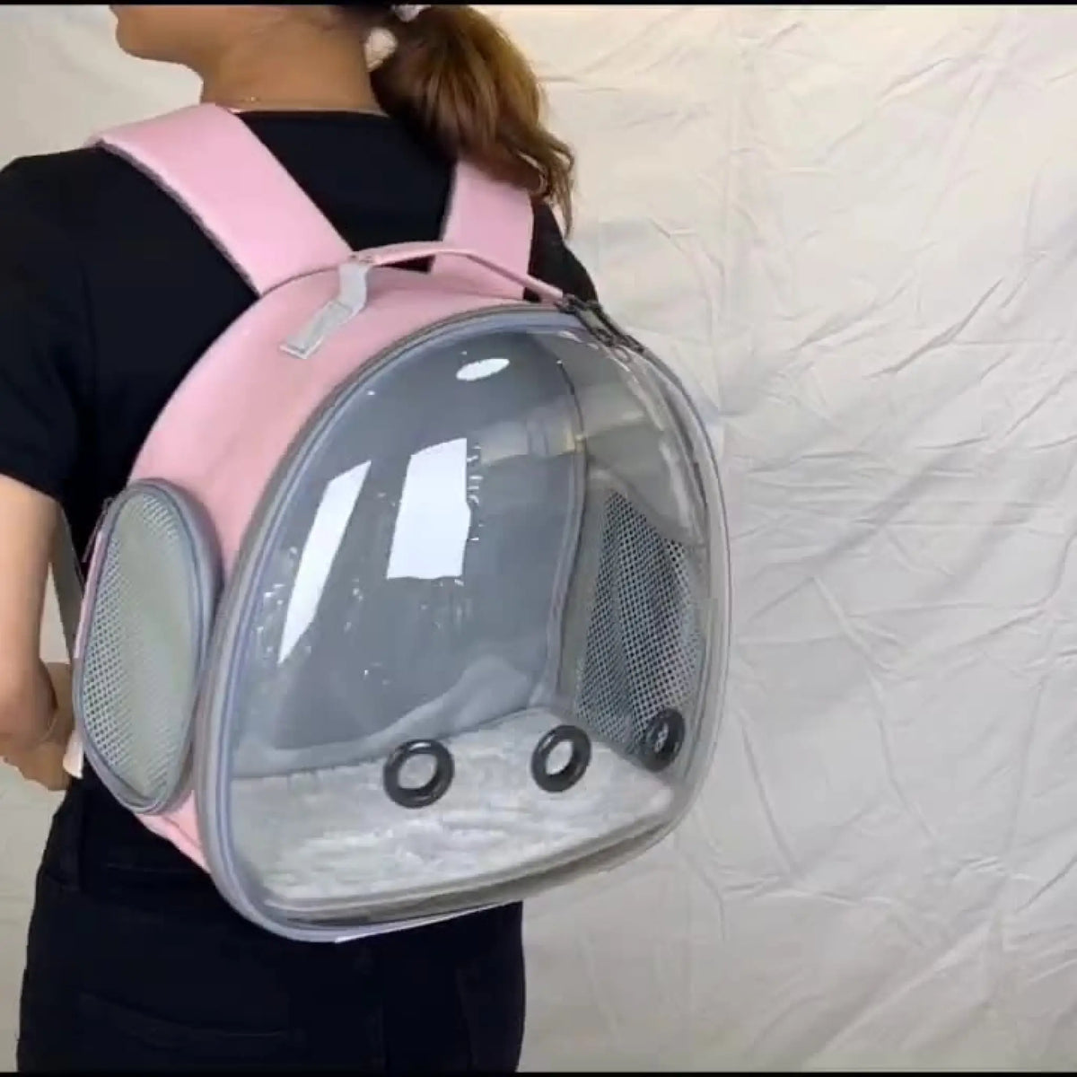 Woman wearing pink bubble pet backpack carrier on her back
